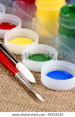 artist brushes with paint jar covers and jars in background
