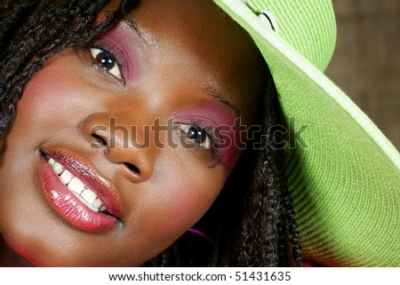 woman with green floppy hat looking at you intensely with a smile