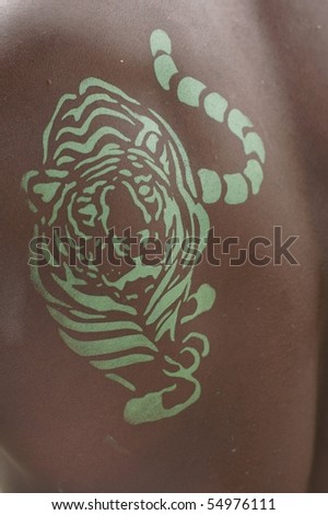 green tiger painted on the back of an african descendant man