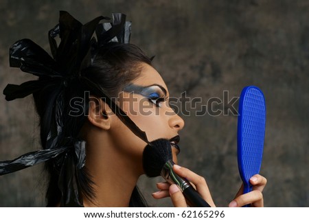 stock photo : young woman of East Indian ancestry applying gothic makeup