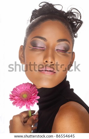 Stunning woman of East Indian ancestry with eyes closed in deep thought holding pink gerber flower