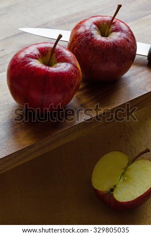 Two and a half Royal Gala English apples and knife on wooden background. Two apples elevated above a half apple. Copy-space, close-up, selective focus, back lit, vertical