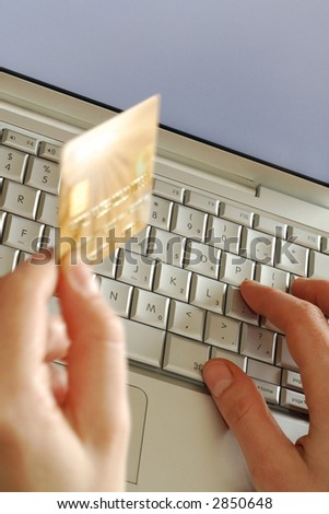 close up of hands on keyboard holding credit card while shopping online using laptop computer