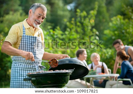 Family Having A Barbecue Party In Their Garden In Summer