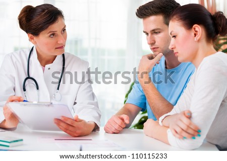 doctor woman offering medical advices to a young couple in office