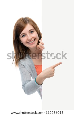 happy smiling teenage girl points her finger at a blank board