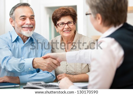 senior couple smiling while shaking hand with financial advisor