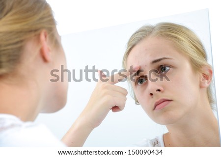 Teenager checking her face for pimple in the mirror