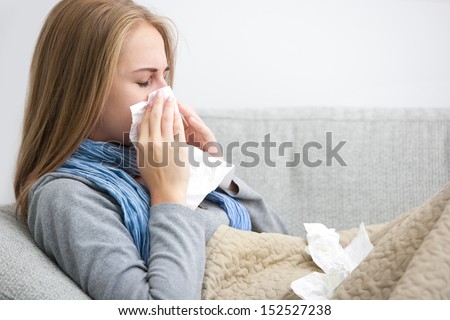 Portrait of a young woman sneezing In to tissue