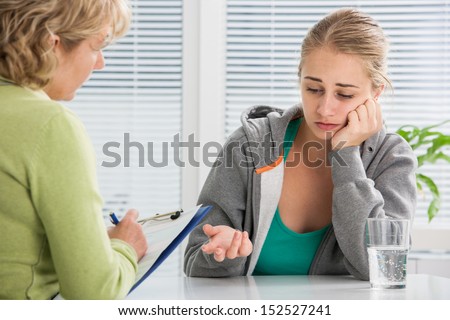 teenage girl suffering with depression in a conversation with therapist or  psychologist