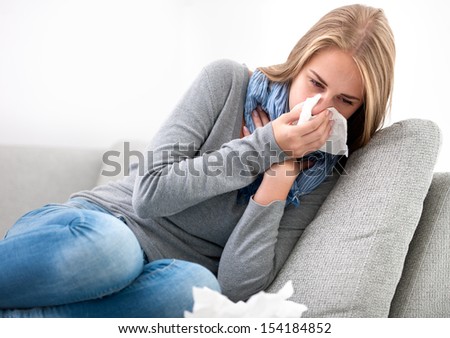 Portrait Of A Young Woman Sneezing In To Tissue