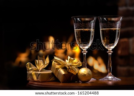 two glasses and gift boxes  in front of fireplace