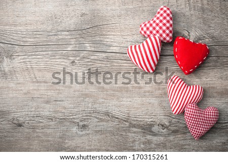 Valentines Day background with patterned textile hearts on old wooden