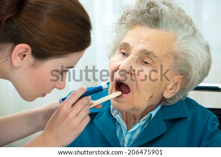 Doctor examines elderly woman for sore throat