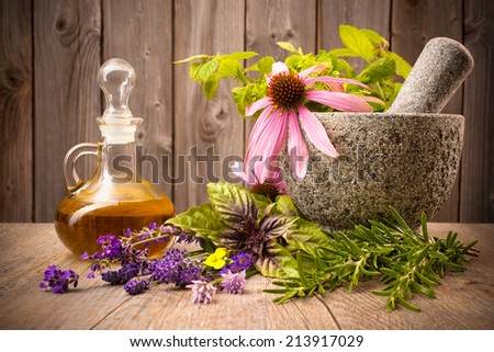 Healing herbs with mortar and bottle of essential oil on wood