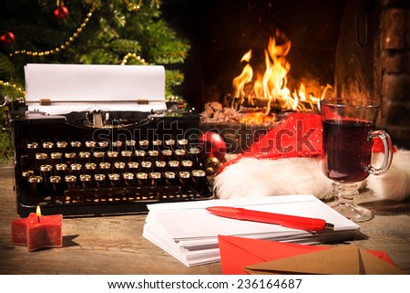 Old typewriter and Santa Claus hat on desk in front of fireplace