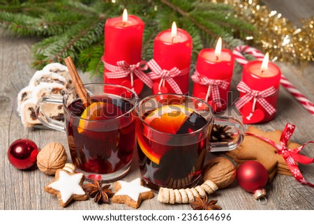 Glasses of red mulled wine on table with burning candles and christmas decorations