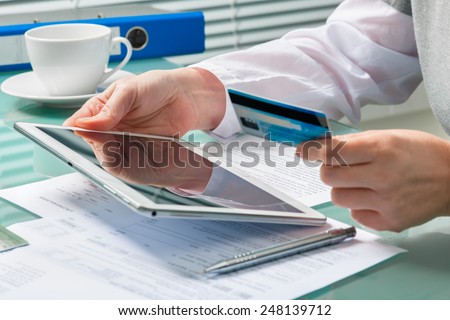 Woman using a credit card and digital tablet for buying on-line