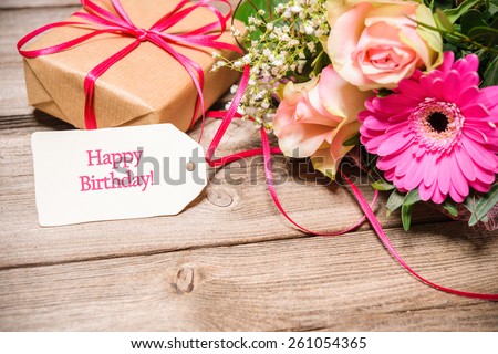 Bunch of flowers and tag with text on wooden background. Happy Birthday