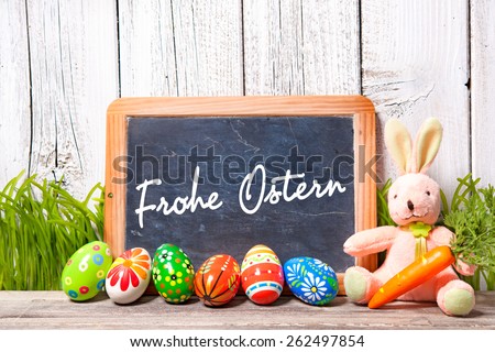 Background for Easter with german text. Decoration with sugar rabbit, eggs and message board