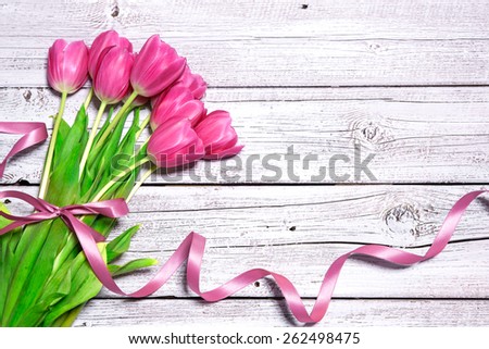 Bouquet of spring pink tulips with ribbon on wooden background