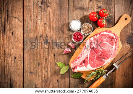 Raw fresh meat rib eye steak and seasoning on wooden background