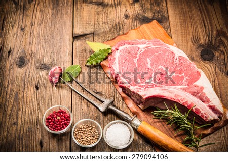 Raw fresh meat rib eye steak and seasoning on wooden background