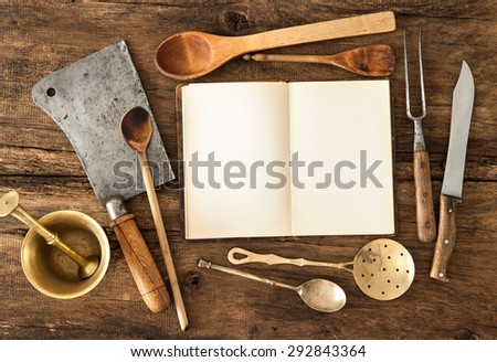 Empty notebook or cookbook and vintage kitchen utensils on wooden table