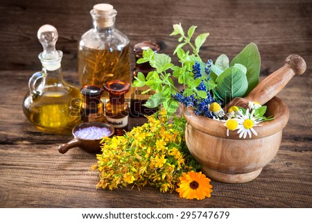 Essential oil, mortar with fresh herbs and bath salt on wooden background