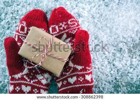 Female hands in winter gloves with christmas gift box
