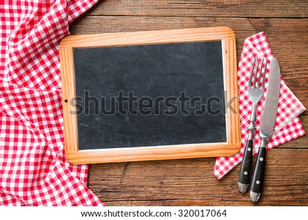 Kitchenware on a blackboard with a red checkered tablecloth