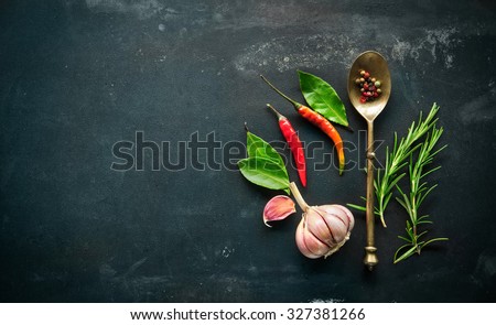 Herbs and spices with old metal spoon on slate background