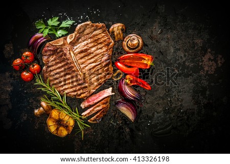 Beef T-Bone steak with grilled vegetables and seasoning on dark background