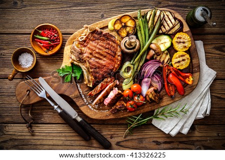 Beef steak with grilled vegetables and seasoning on serving board block