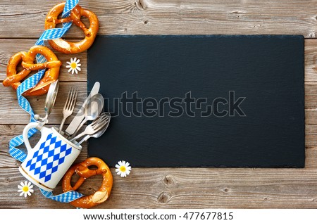 Bavarian pretzels with silverware and beer stein on wooden board. Background for Oktoberfest