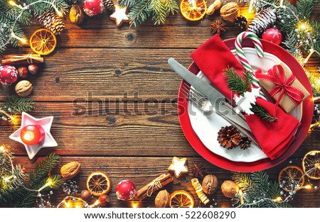 Christmas table setting with fir tree, oranges, cones, nuts, spices, cookies and lights on a wooden table
