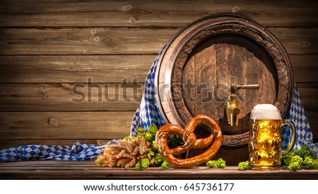 Oktoberfest beer barrel and beer glass with wheat and hops on wooden table