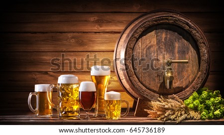 Oktoberfest beer barrel and beer glasses with wheat and hops on wooden table