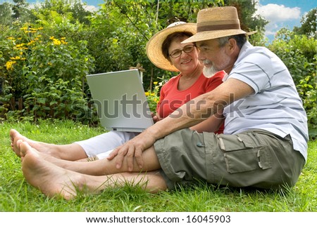 senior couple in garden at leisure with laptop computer