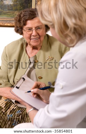 Senior woman is visited home by her doctor or caregiver at home. In the background is a picture from my portfolio