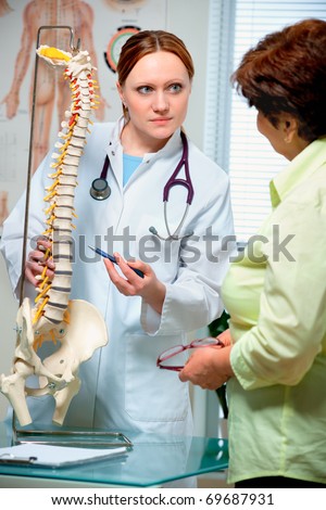 Physical Therapist shows the problem areas on the model of the spine to patient and explains the cause of her pain.