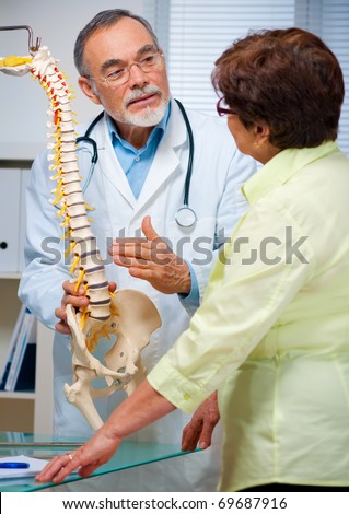 Physical Therapist shows the problem areas on the model of the spine to patient and explains the cause of her pain.