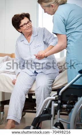 Nurse helps a patient to get up in hospital