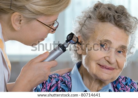 Doctor performing ear exam with otoscope on a  senior patient