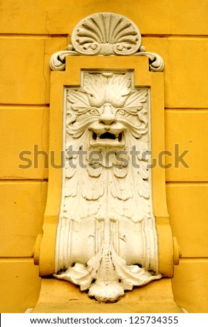 Architectural detail of a lion\'s head on the yellow wall of a building
