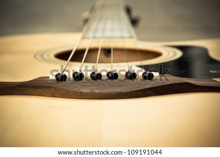 Macro shot down the fretboard of acoustic guitar with shallow depth of field