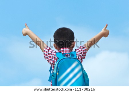 Under the blue sky with a bag on her back asian boy, thumbs up, refueling position. 4 years old