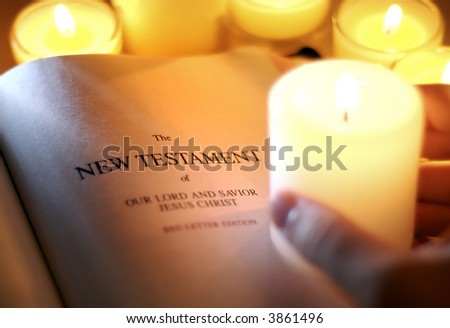 Hand Holding Candle Illuminating New Testament