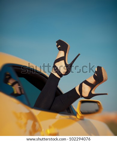 woman\'s legs with shoes by the way the car window on vacation. Concept of happiness and fun during the trip in the summer