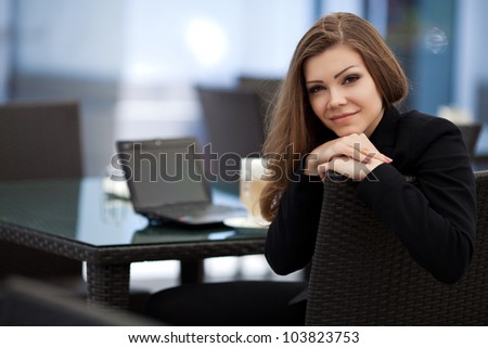 Portrait of beautiful smiling woman sitting in a cafe with laptop outdoor